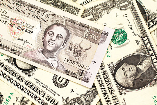 A close up image of a one Ethiopian birr bank note on a background of American one dollar bills