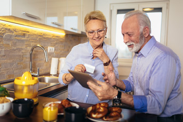Modern senior couple shopping online with tablet and credit card