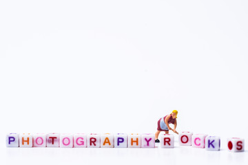 Miniature figurine woman fixing adjusting a Group Of Letters forming Words Spelling 