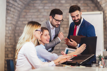 Business colleagues working on laptop in modern office.