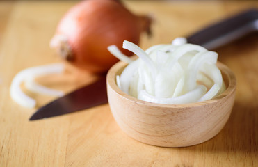 Sliced onion in a bowl on wooden board preparing for cooking
