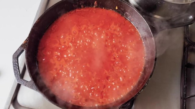 Fresh traditional and simple tomato sauce bubbling and cooking, from birds eye view. Nonna's recipe.