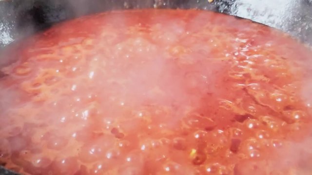 Fresh traditional and simple tomato sauce bubbling and cooking from low side view. Nonna's recipe.