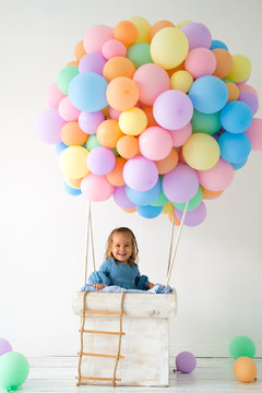 a little girl is standing in the basket of a balloon. photo zone to celebrate a birthday