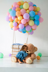 A little girl is celebrating her birthday. Big Teddy bear in a birthday present.