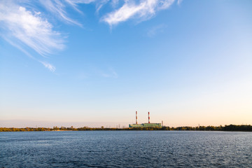 Naklejka premium Power station on the background of a golden sunset behind the lake