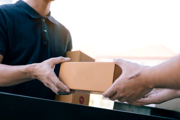 Asian cargo carrier holds a cardboard box with the package inside and the recipient is signing the...