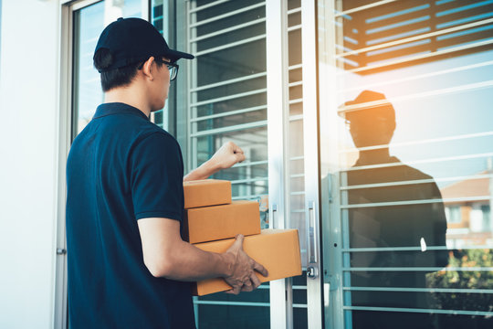 Young Asian Courier Is Using The Hand Of The Knock At The Door To Deliver The Goods.