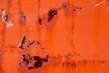 Old paint of red-orange color on dirty, rusty iron surface.