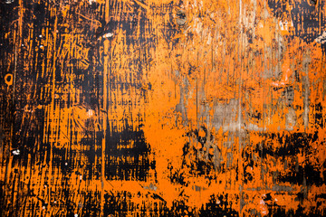Old wooden surface, covered with two colors of paint, black and orange, which have lost their color in the open sun and in some places fell off, revealing the background