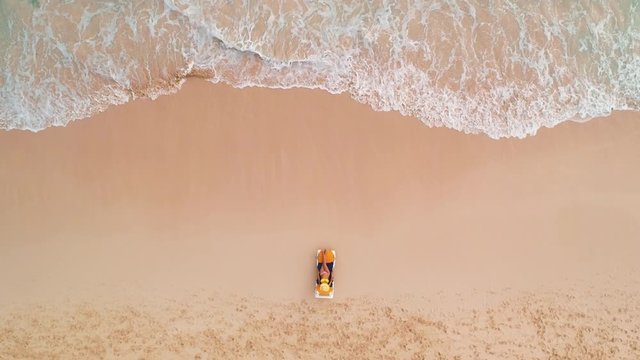 Beach vacation in paradise tropical island, sexy suntan woman relaxing on idyllic summer background in clear water and beach. Top view aerial drone video