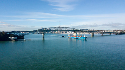 Fototapeta na wymiar cargo ship travelling pass Auckland Harbour Bridge, with Auckland City as background