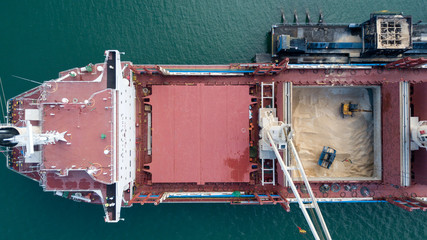 Cranes working on cargo ship transporting sugar, Aerial pullback viewing work from above