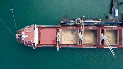 Top down aerial view of Container ship unloading sugar shipment at cargo depot 4k