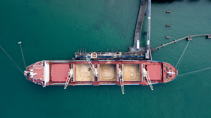 Large cargo ship aerial revealing pan at high angle, sugar being offloaded at port 4k
