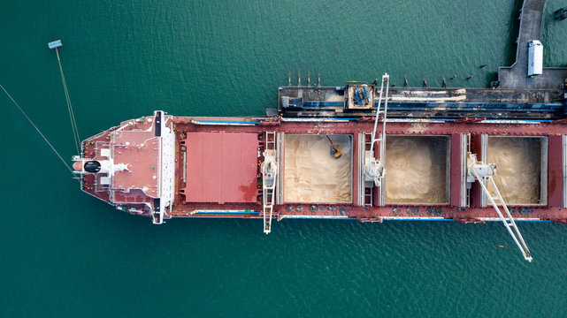 Top down aerial view of Container ship unloading sugar shipment at cargo depot 4k