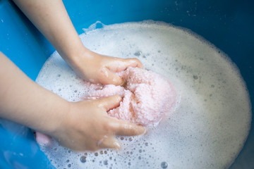 women's or children hands clean the towel in the basin with soapy detergent, with soap cleaner