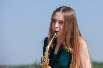 Beautiful brunette plays the saxophone in the park