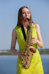 Young woman with saxophone in the park