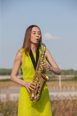 Young beautiful saxophonist with saxophone - outdoor in nature