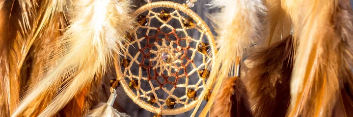 Banner aus handgefertigtem Traumfänger mit Federn, Fäden und Perlen am Seil hängend © dashtik