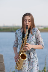Young woman with saxophone in the park