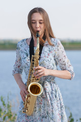 Young woman with saxophone in the park