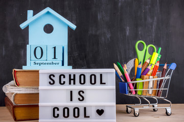 Set of colored pencils and markers for school in a shopping cart. Lettering School is cool on a...