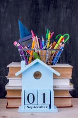 Set of colored pencils and markers for school in a shopping cart. 1 of September calendar on a pile...
