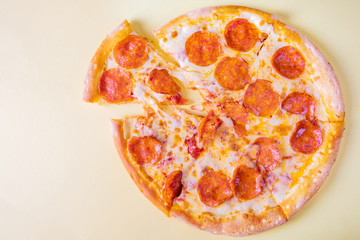 Pepperoni pizza on a yellow background. Concept of italian food, fast food, unhealthy food. Salami, cheese. Bright image, minimalism, top view, flat lay. Place for text.