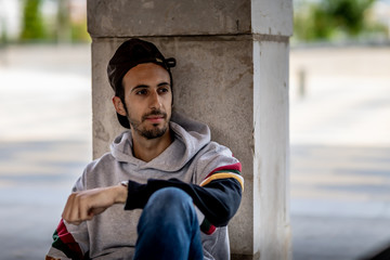 Portrait of a young man with beard and casual clothes sitting in an urban park