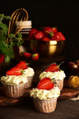 Cupcakes with strawberries on a dark background. Still life.