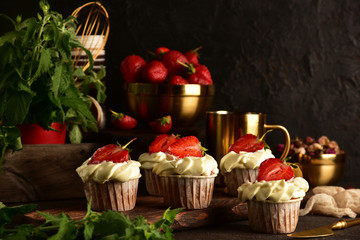 Cupcakes with strawberries on a dark background. Still life.