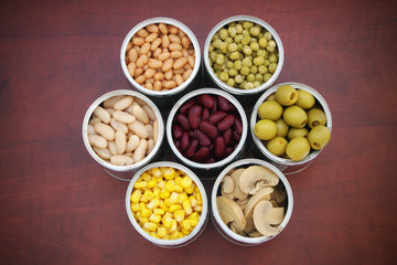 Seven tin cans with canned food on wooden table 