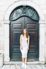 Fototapeta na wymiar Summer photo shoot on the streets of Kotor, Montenegro. Beautiful girl in white dress and hat.