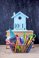 Set of colored pencils and markers for school in a shopping cart. 1 of September calendar on a pile...