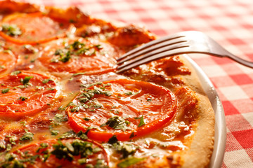 Close up eating piece of pizza with a fork, Pizza Margarita. Delicious hot food sliced and served on white platter. Menu photo, Italian fast food.