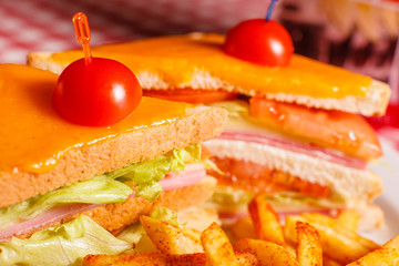 Close up Tasty grilled sandwich in the restaurant. Club sandwich with ham, tomato, cheese and lettuce. Served with French fries