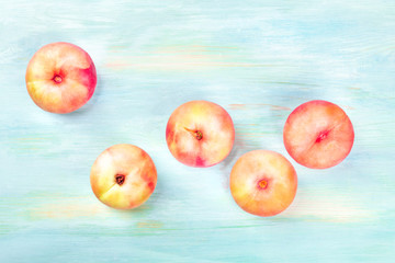 An overhead photo of vibrant organic flat saturn peaches, shot from the top on a teal background...