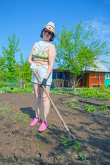 Beautiful mature woman handles the summer cottage hoe.