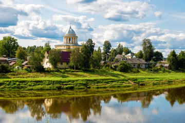 View of the left bank of the river Msta and the Church of the Assumption of the Blessed Virgin Mary on a summer day