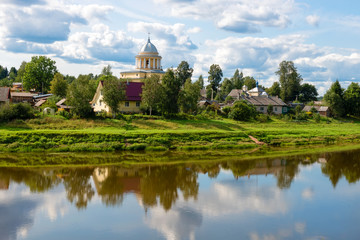 View of the left bank of the river Msta and the Church of the Assumption of the Blessed Virgin Mary on a summer day