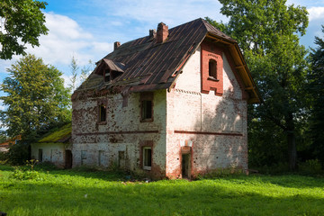 Fototapeta na wymiar Collapsing two-story brick house in the park on a summer day