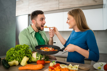 Young couple is preparing meal in their kitchen. 