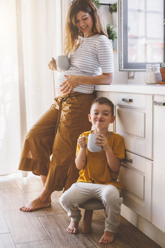 Pregnant Mom With Kid Drinking Tea Together In The Kitchen