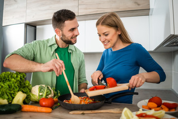 Young couple is preparing meal in their kitchen. 