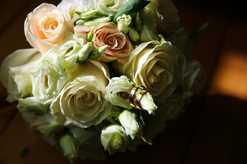 Beautiful wedding bouquet. Roses in pastel colors. Bridal flowers. Golden rings for couple.