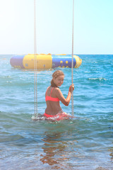 Happy smiling pretty young teenager girl on a swing in the sea