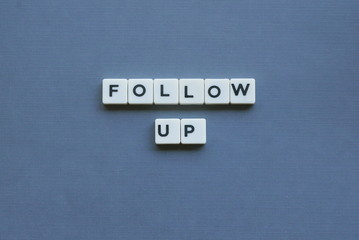 ' Follow Up ' word made of square letter word on grey background.