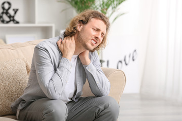 Young man suffering from neck pain at home